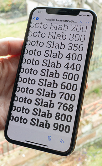 Photo of my hand holding an iPhone up to the window, on screen is Roboto Slab in eleven different weights including non-standard. 356 stands out the most to me you can see the contrast with 300 and 400